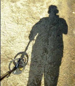 Ground shadow of a person metal detecting.
